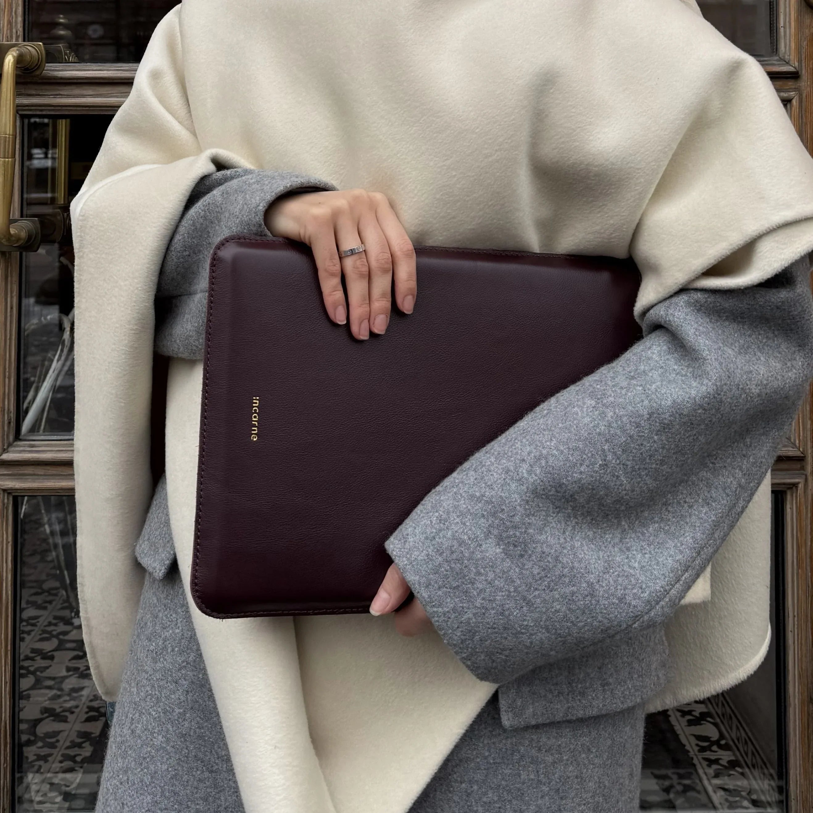 MacBook усередині бордового шкіряного чохла ClineUp, зарядний кабель під’єднаний збоку