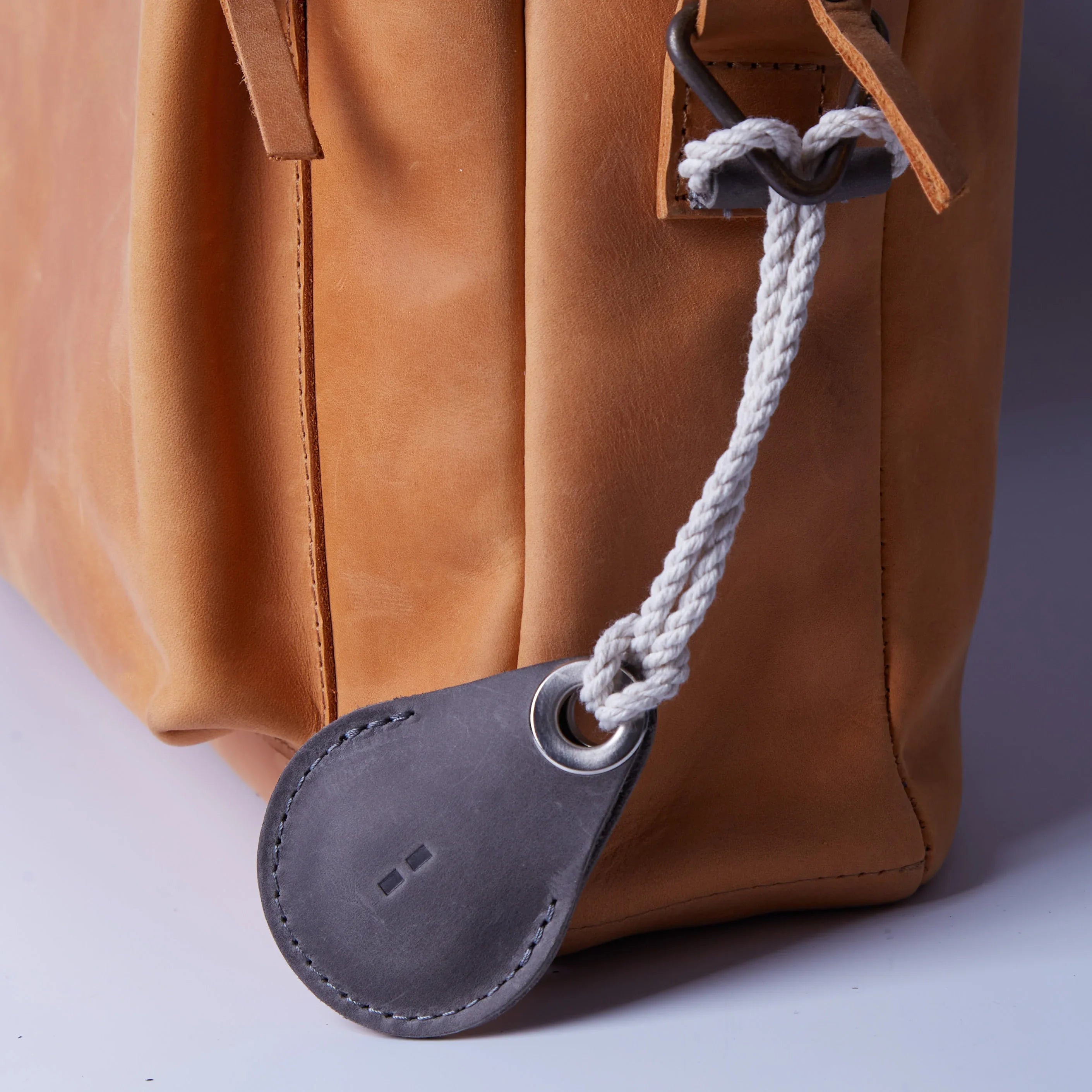 Набір аксесуарів INCARNE з сірим шкіряним чохлом для Apple AirTag на дерев’яній поверхні