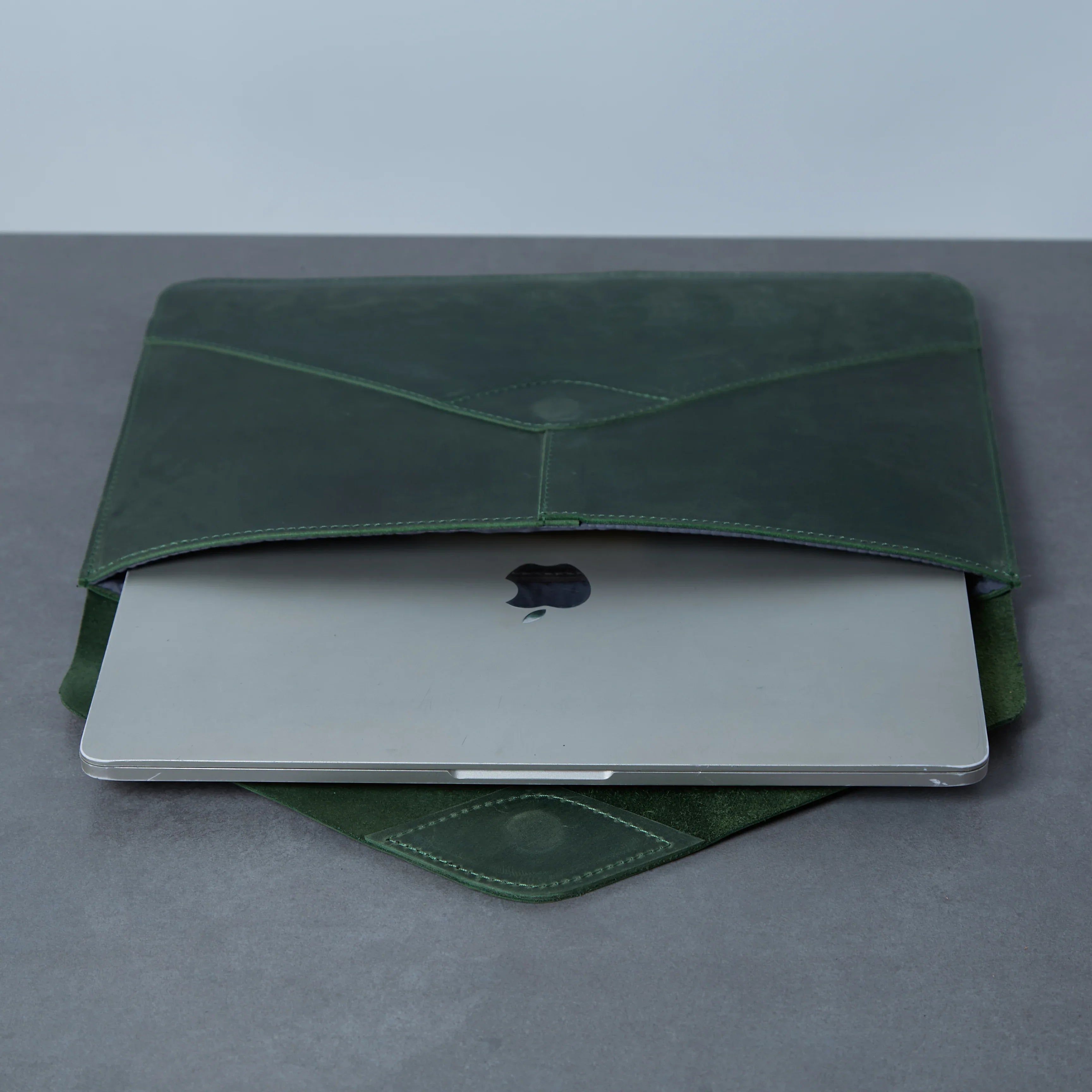 Відкритий зелений чохол Message з MacBook всередині, фетрова та текстильна підкладки захищають ноутбук