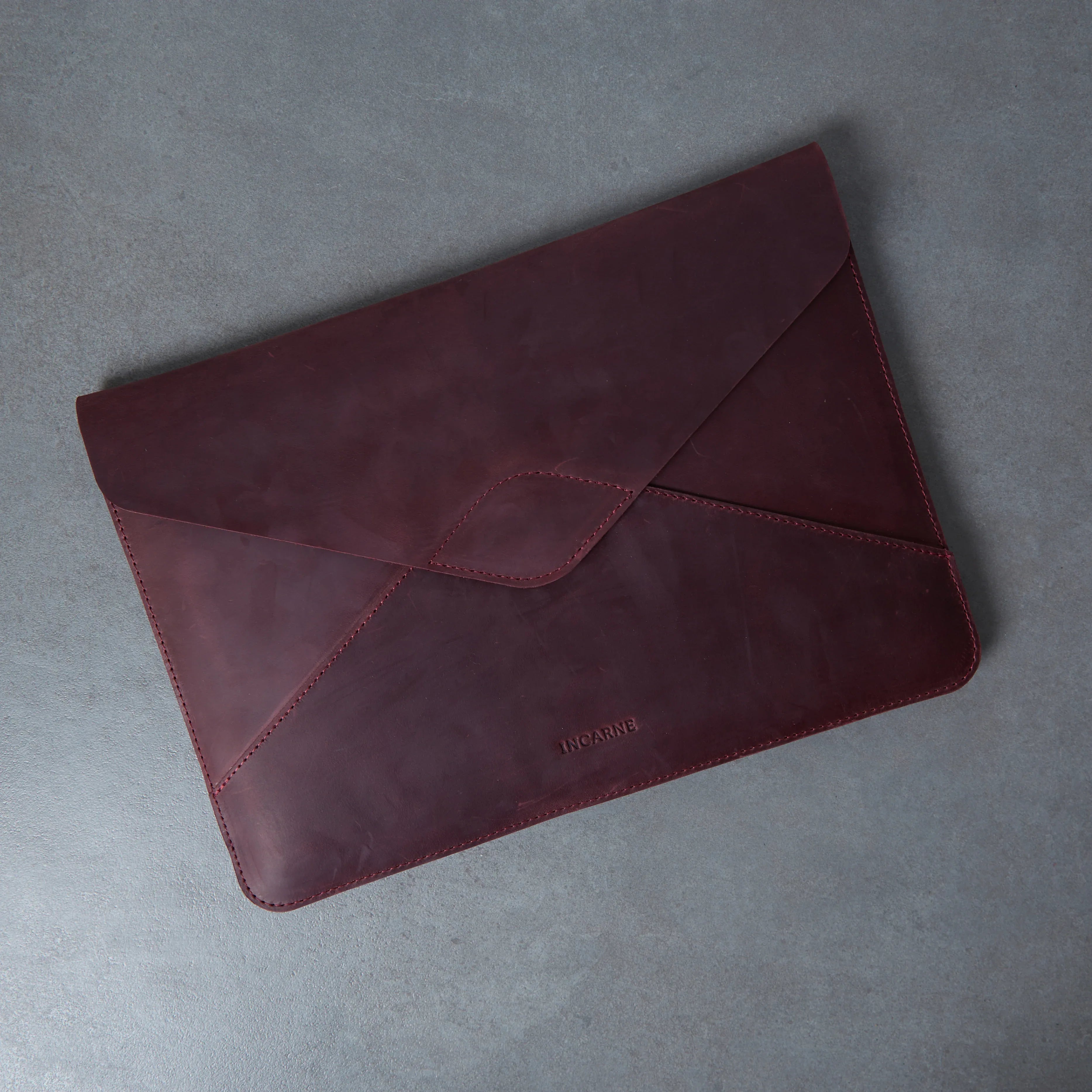 Бордовий шкіряний чохол Message для MacBook M2 на столі, лаконічний аксесуар у стилі конверта для ноутбука