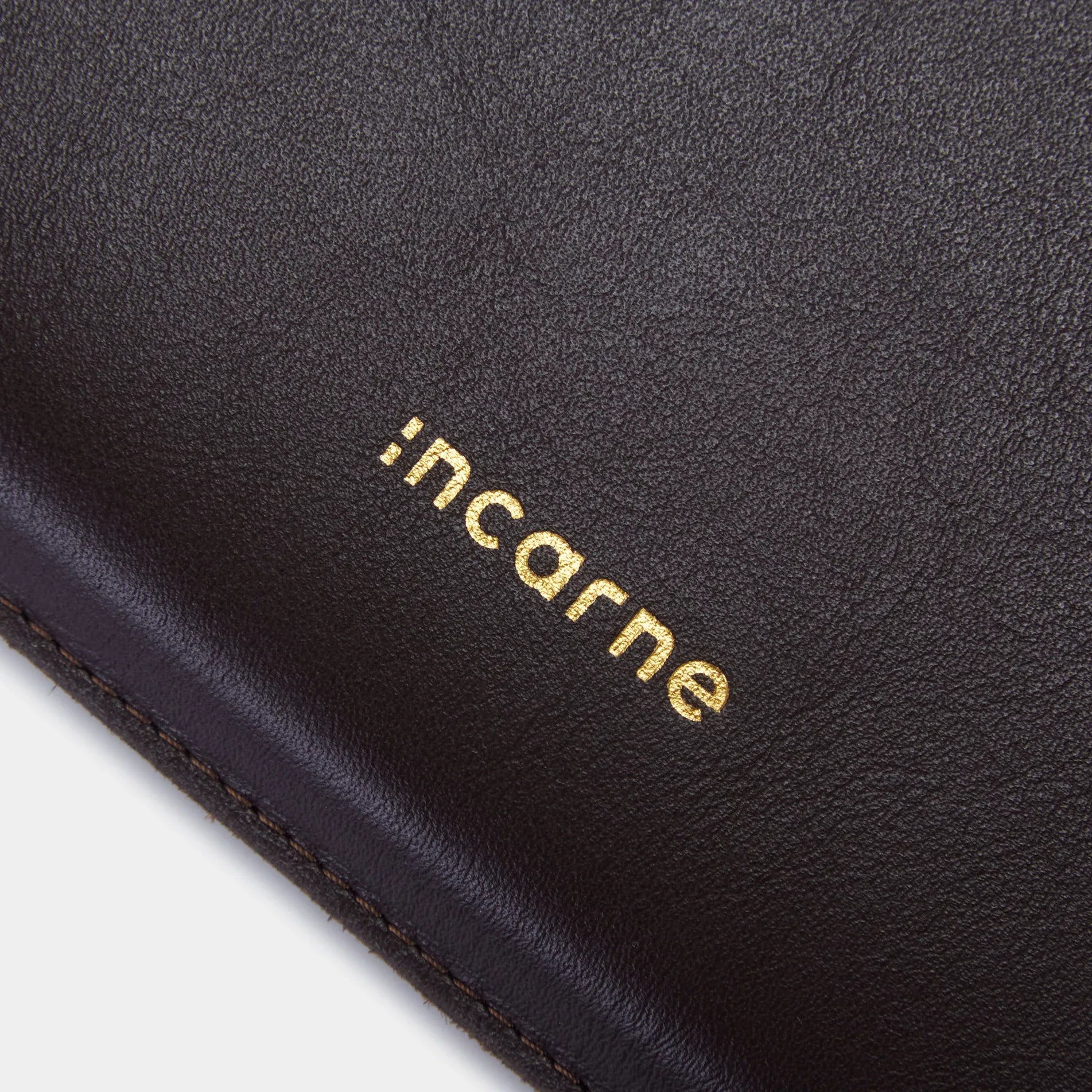 Золотисте тиснення логотипу INCARNE на шоколадному шкіряному чохлі Cline