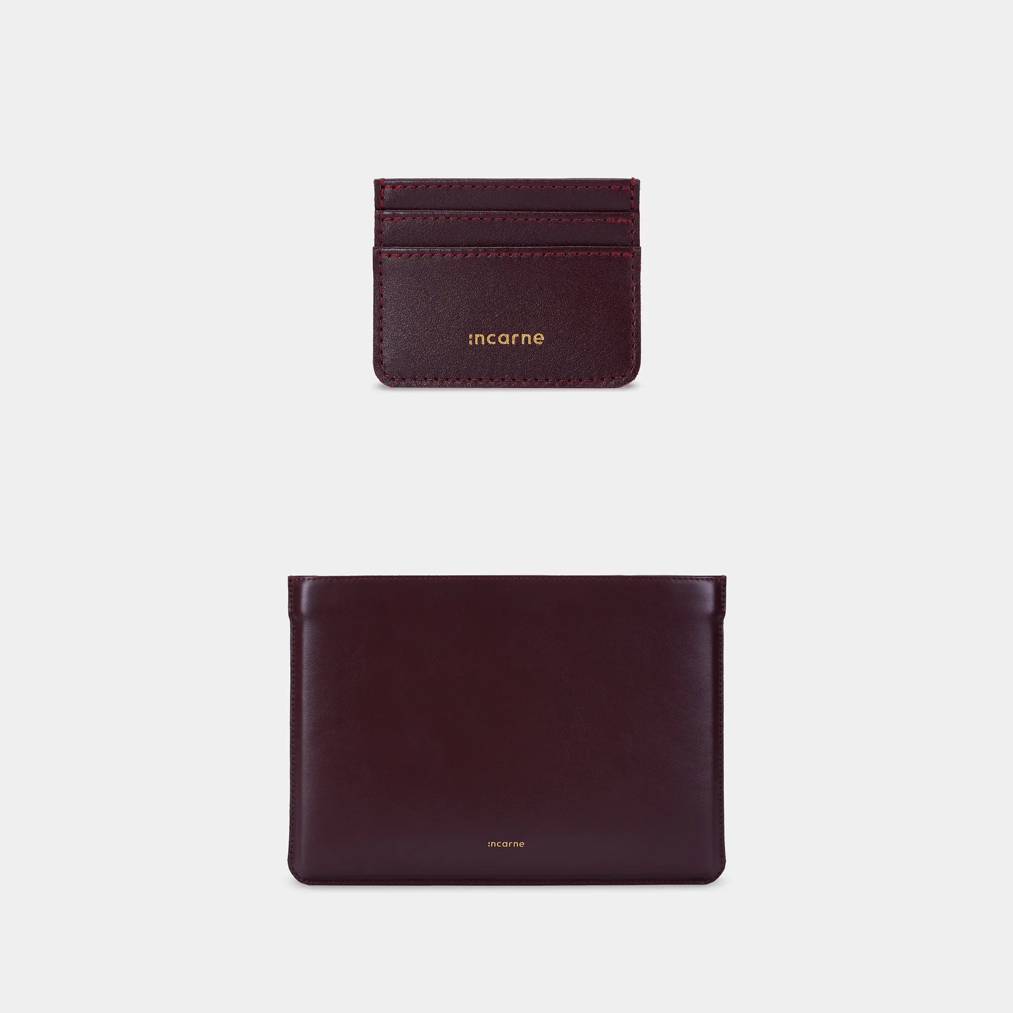 Подарунковий сет INCARNE Cline і Minimal з натуральної шкіри бордо на столі, чохол для MacBook та кардхолдер у мінімалістичному стилі